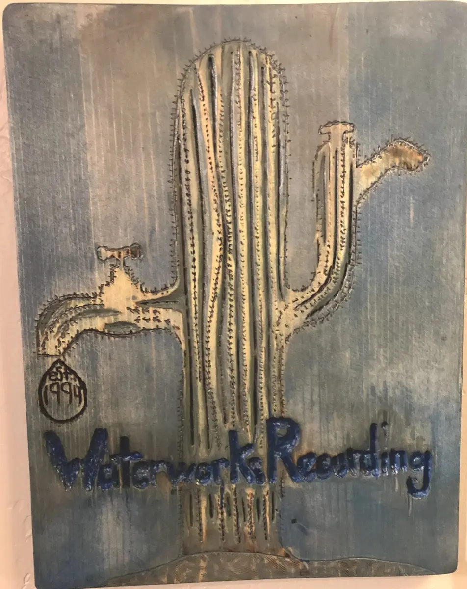 Carved and painted wooden plaque of the saguaro-and-faucet logo, signed Waterworks Recording, est. 1994.